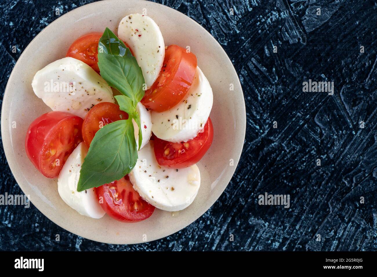 Nahaufnahme von Tomaten und Mozzarella-Kreisen mit Basilikumblättern. Servieren von italienischem Caprese-Salat. Flaches Lay. Weicher Fokus. Draufsicht Stockfoto