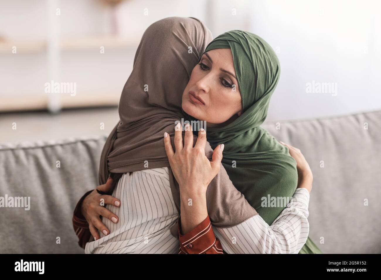 Ältere Muslimische Mutter Umarmt Unglücklich Erwachsene Tochter Trägt Hijab Indoor Stockfoto