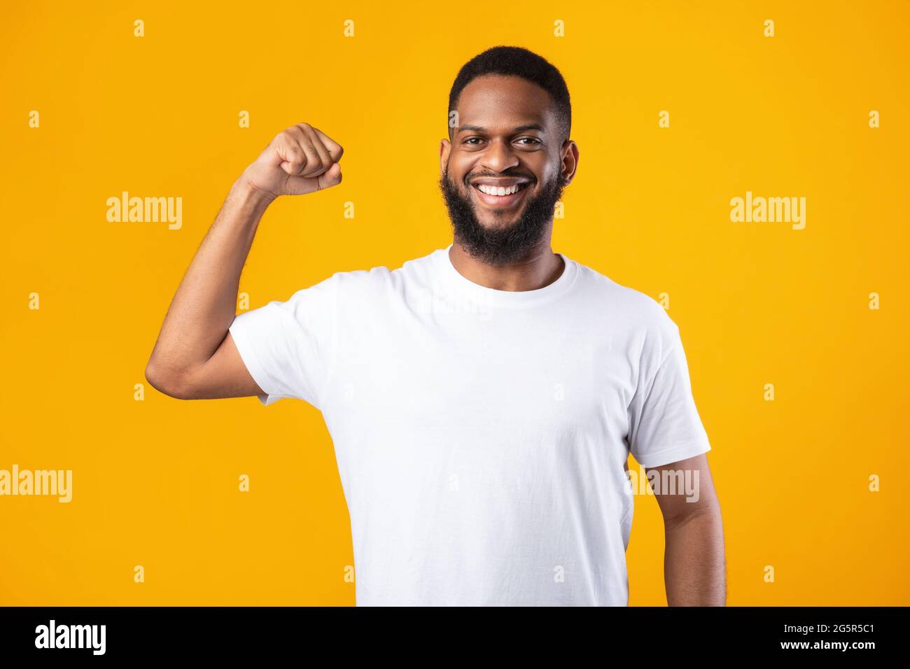 Fröhlicher Schwarzer Kerl Zeigt Biceps Muskeln Posiert Auf Gelbem Hintergrund Stockfoto