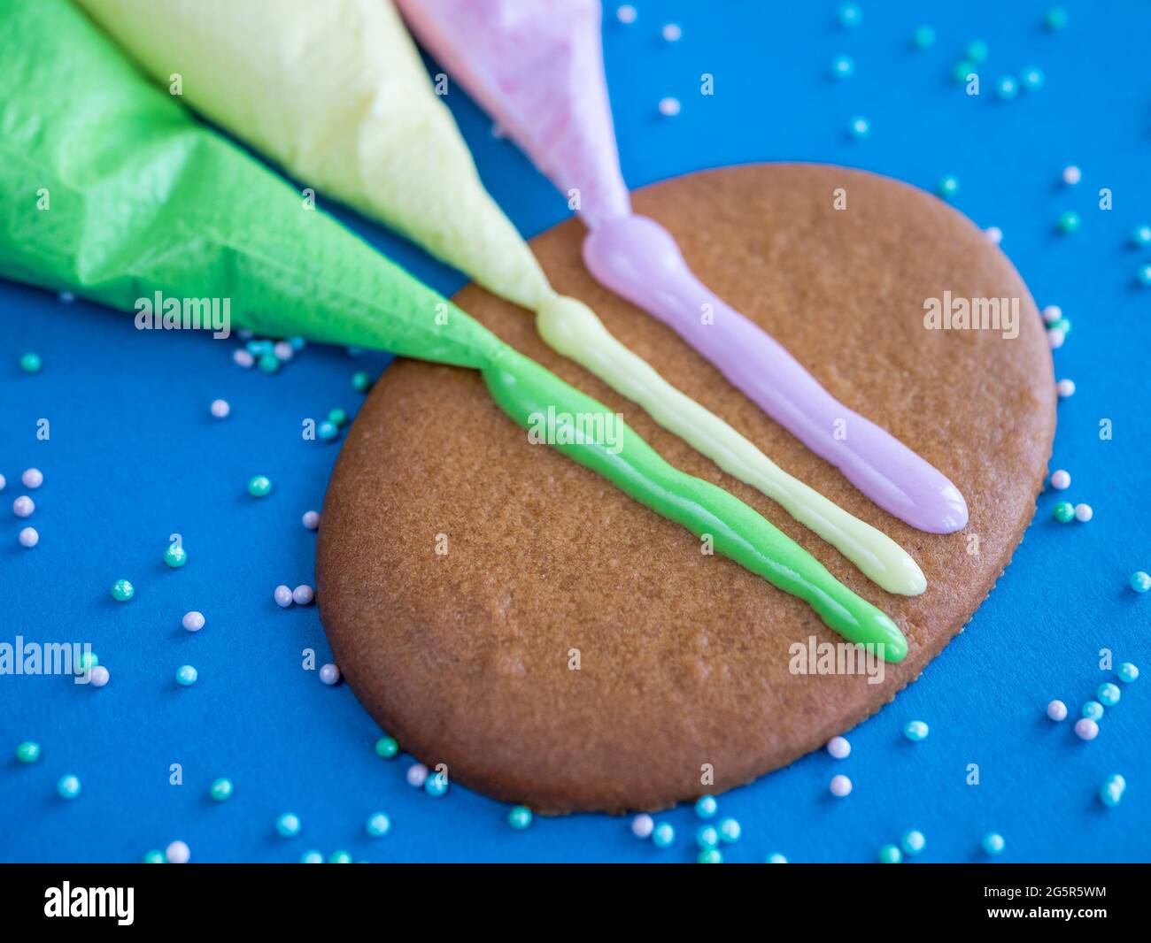 Lebkuchen und farbige Vereisung für Cookie Dekoration auf blauem Hintergrund mit Streuseln, Nahaufnahme Stockfoto