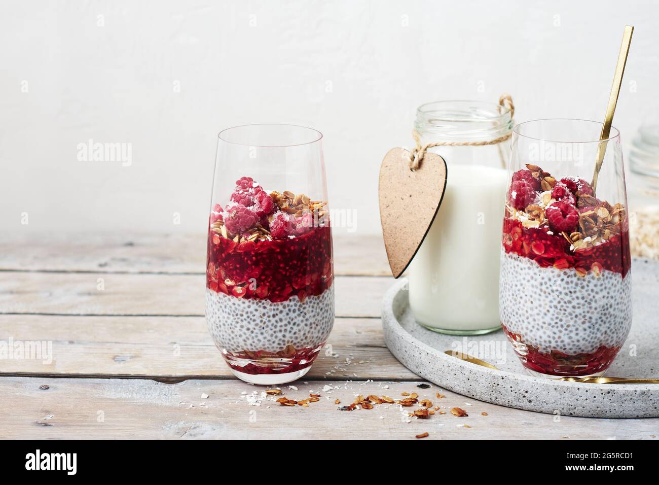 Zwei Gläser Chia Pudding mit Müsli und Himbeeren. Stockfoto
