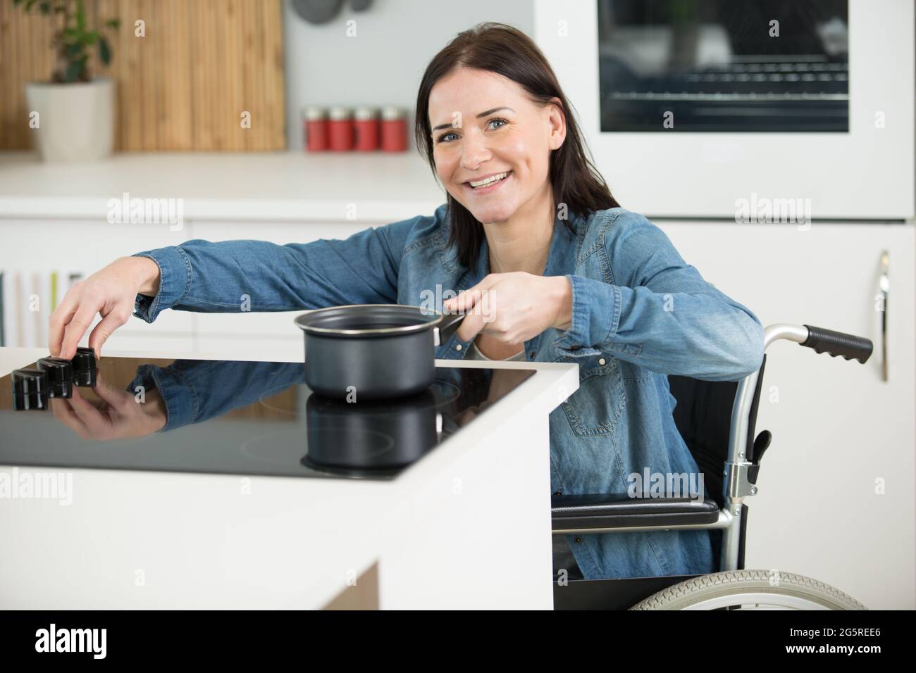 Glückliche behinderte Frau im Rollstuhl Kochen Abendessen Stockfoto