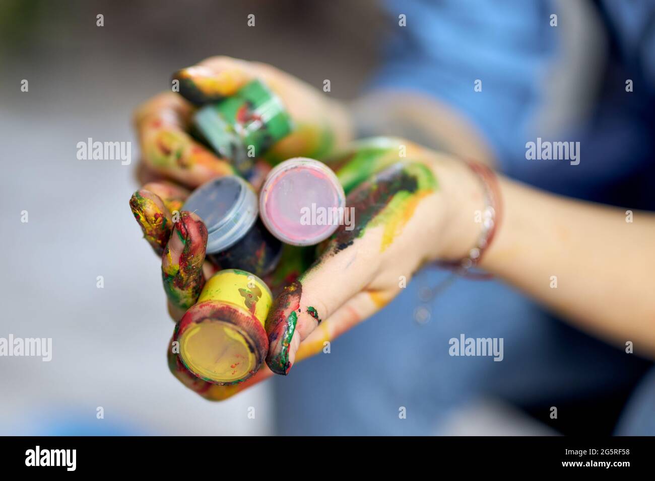 Nahaufnahme der weiblichen Hände mit bunten Acrylölfarben in Gläsern Stockfoto