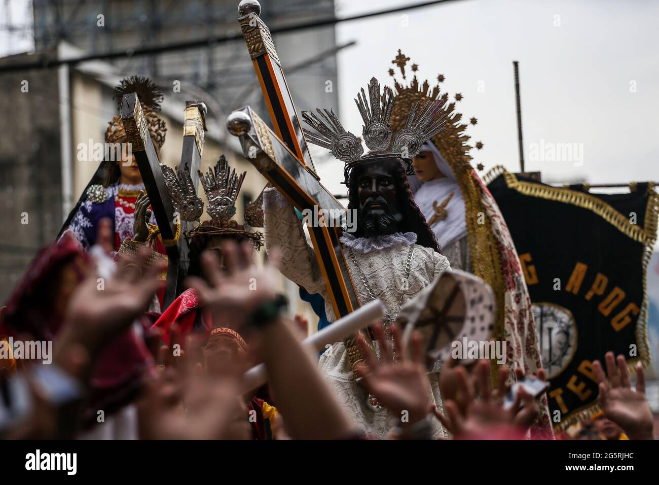 Philippinisch-katholische Anhänger heben ihre Hände und Handtücher, während Priester vor dem Fest des Schwarzen Nazareners in Manila, Philippinen, Heiliges Wasser auf die Repliken des Schwarzen Nazareners streuen. Stockfoto