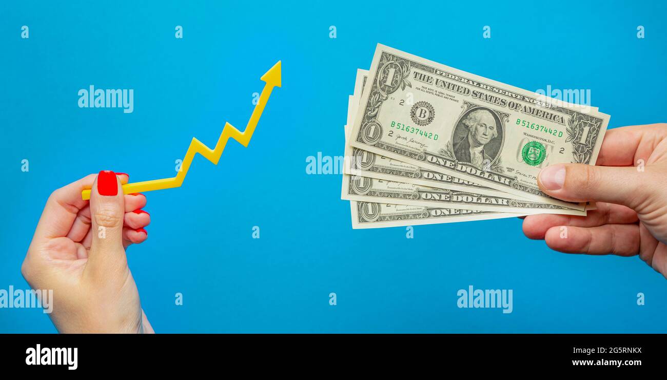 Inflation, Dollar-Hyperinflation. Steigende Preise. Banner mit blauem Hintergrund. Ein Dollarschein in der Hand eines Mannes auf blauem Hintergrund. Inflation Stockfoto