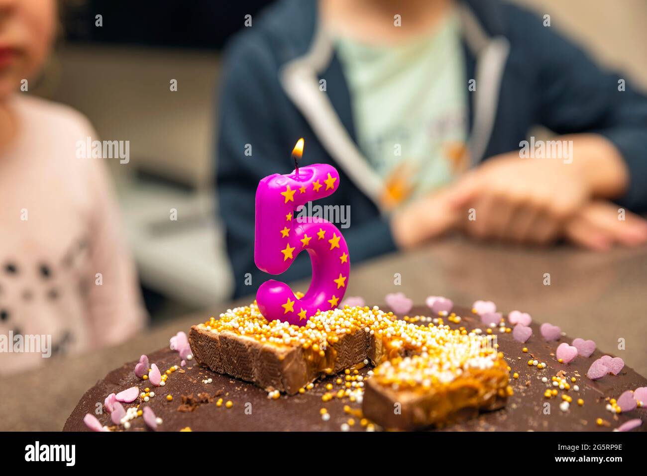 Geburtstag 5 Jahre. Kinder am Tisch essen Kuchen. Kerze Nummer fünf, Flamme. Geburtstagsfeier Konzept Stockfoto