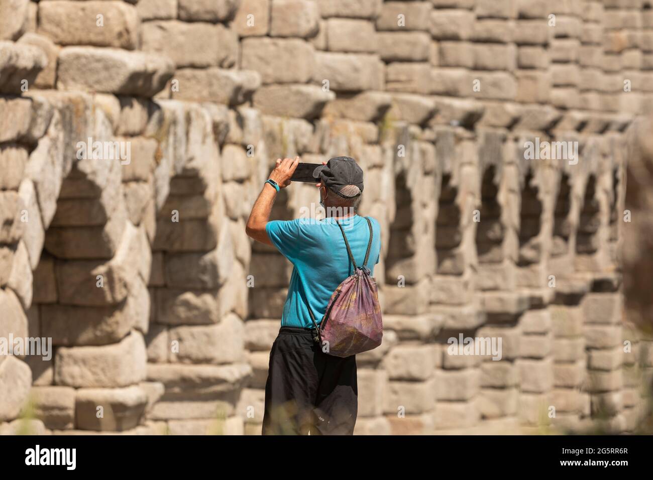 Segovia, Spanien - 2. Juni 2021: Ein älterer Erwachsener, wahrscheinlich ein ausländischer Tourist, fotografiert die Granitsäulen des Aquädukts von Segovia Stockfoto