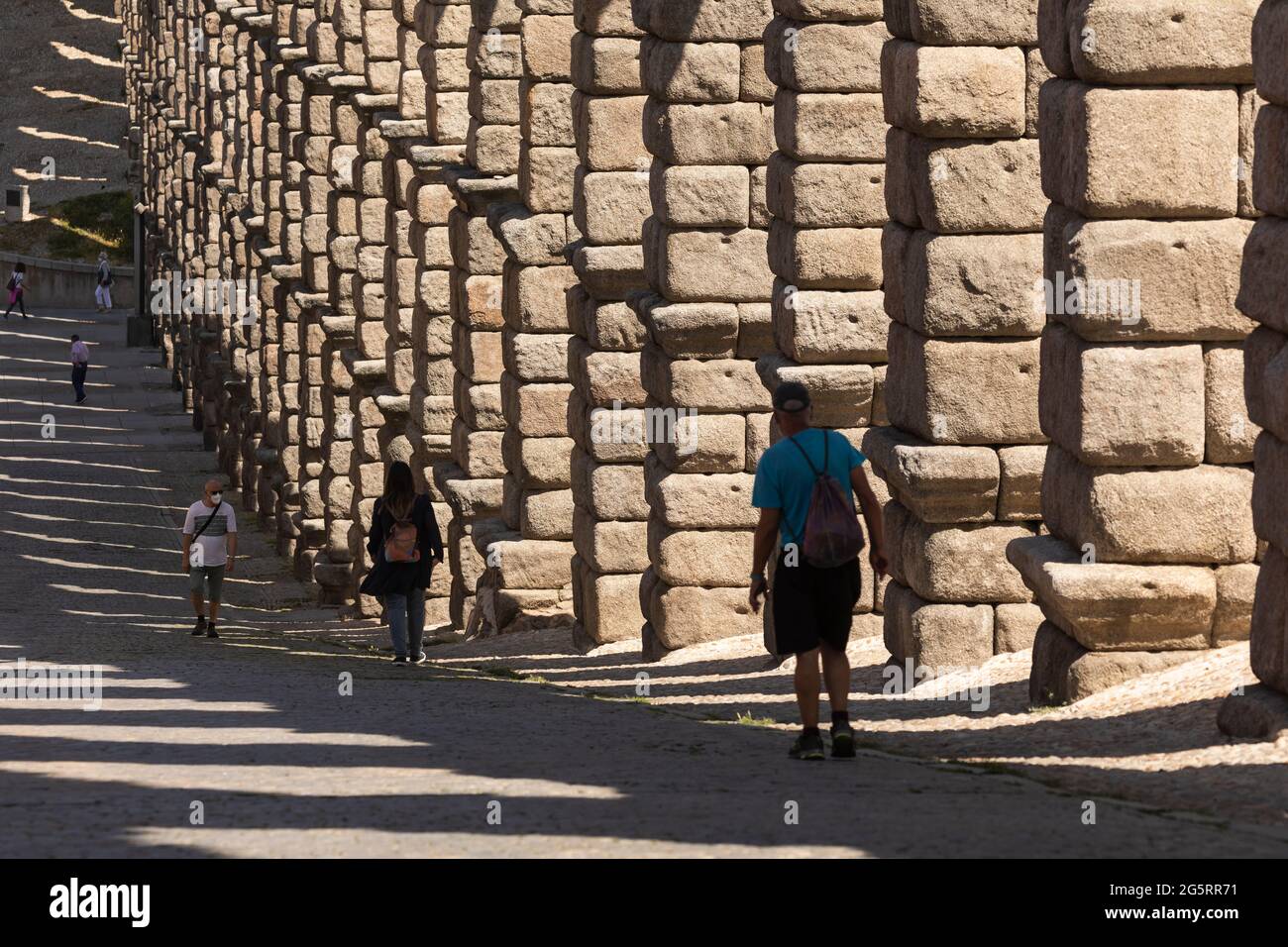 Segovia, Spanien - 2. Juni 2021: Detail der riesigen Granitsäulen des Aquädukts von Segovia und einiger Menschen von der Teodosio el Grande Straße Stockfoto