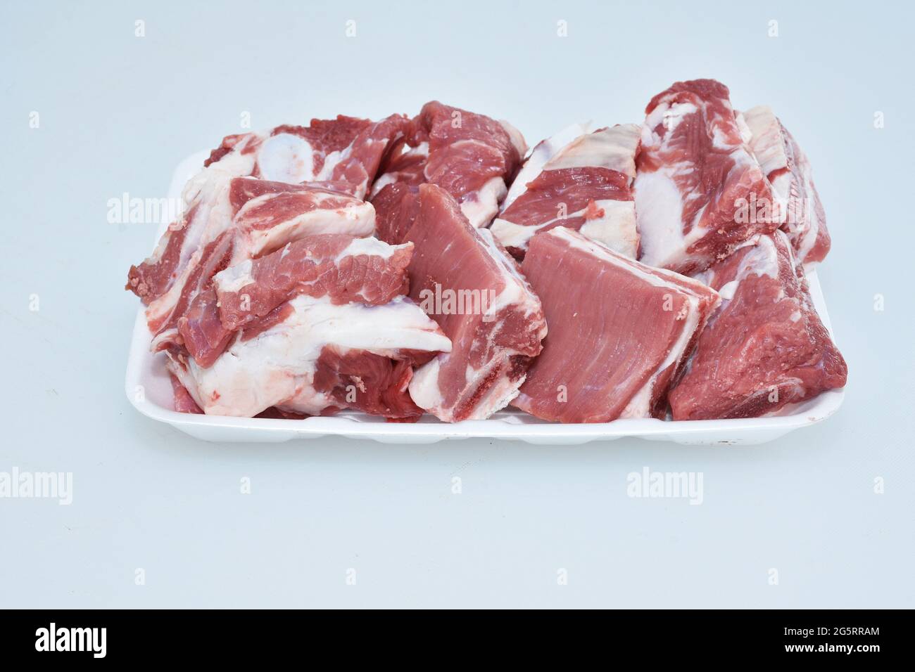 Gehackte Lammrippen auf einem Teller auf weißem Hintergrund, rohes Fleisch vom Hammelfleisch, geschnitten Stockfoto