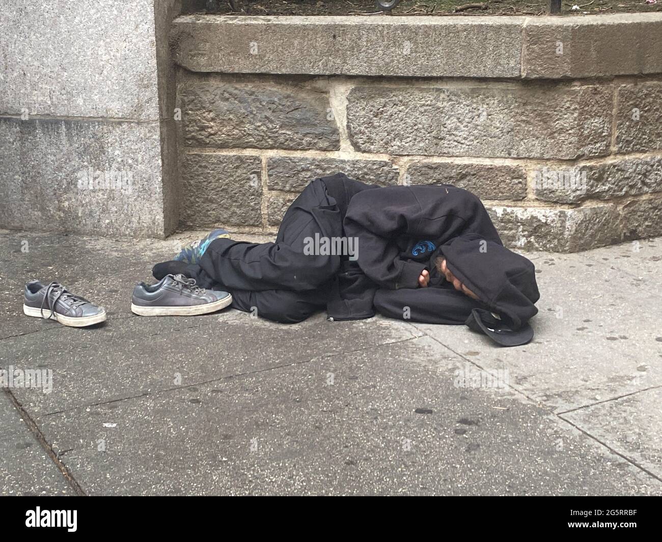 Obdachloser schläft auf dem Bürgersteig an der 6th Avenue und 40th Street beim Bryant Park in Manhattan, ein sehr sichtbarer Ort. Stockfoto