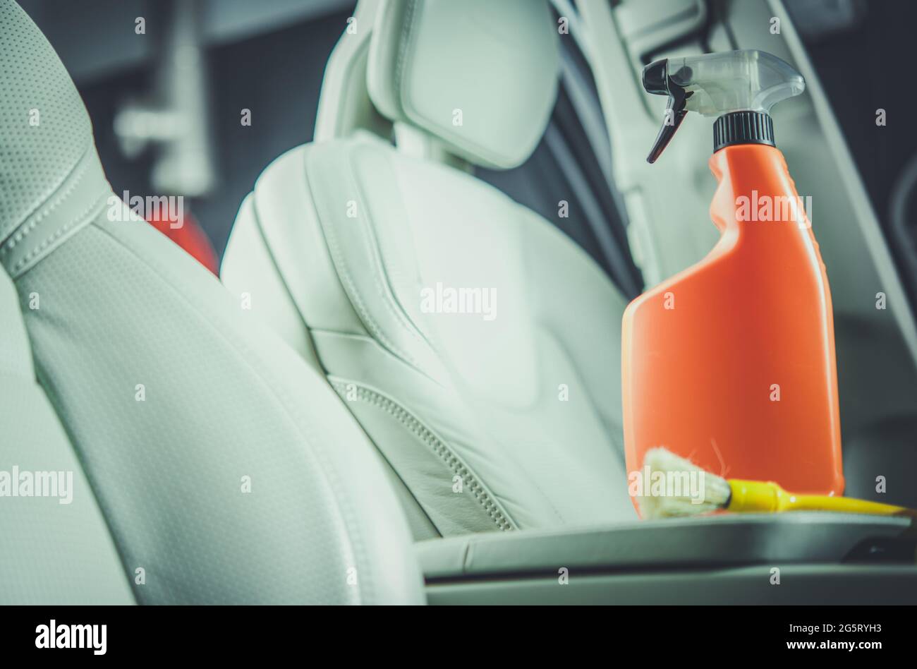 Waschmittel für Leder im Innenraum des Autos in orangefarbener Flasche. Thema Fahrzeugwartung. Stockfoto
