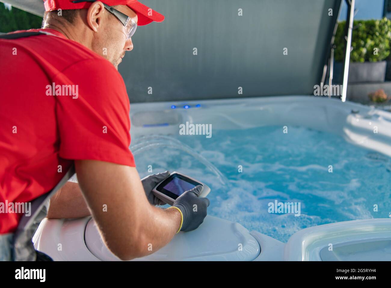 Kaukasischer Garten SPA Techniker in seinen 40er Jahren Testen Whirlpool Remote in SPA Pavillons. Stockfoto