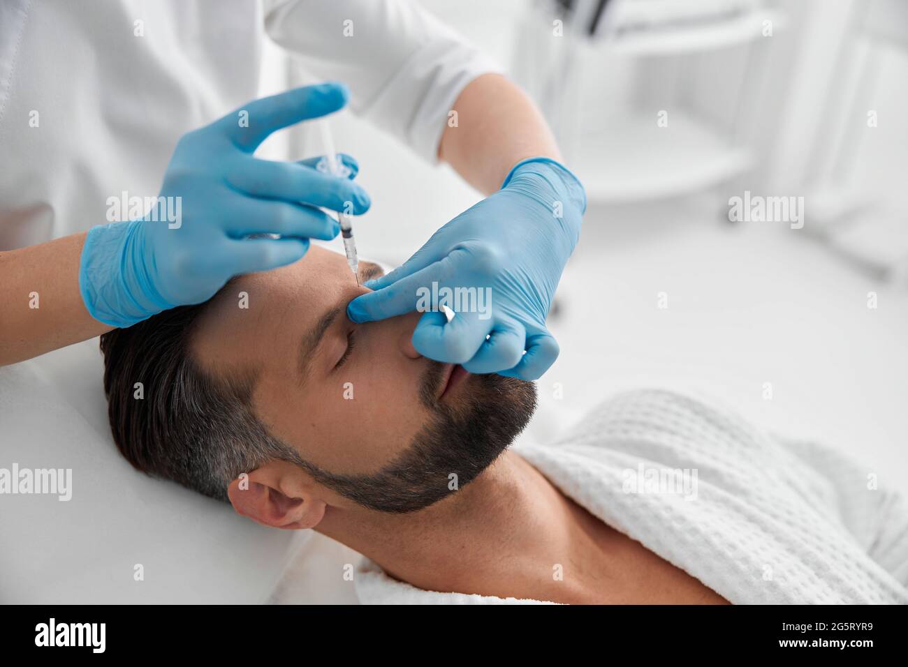 Attraktiver Mann mittleren Alters durchläuft Nasenbrücke Füllstoff Verfahren in der Kosmetologie Klinik Stockfoto
