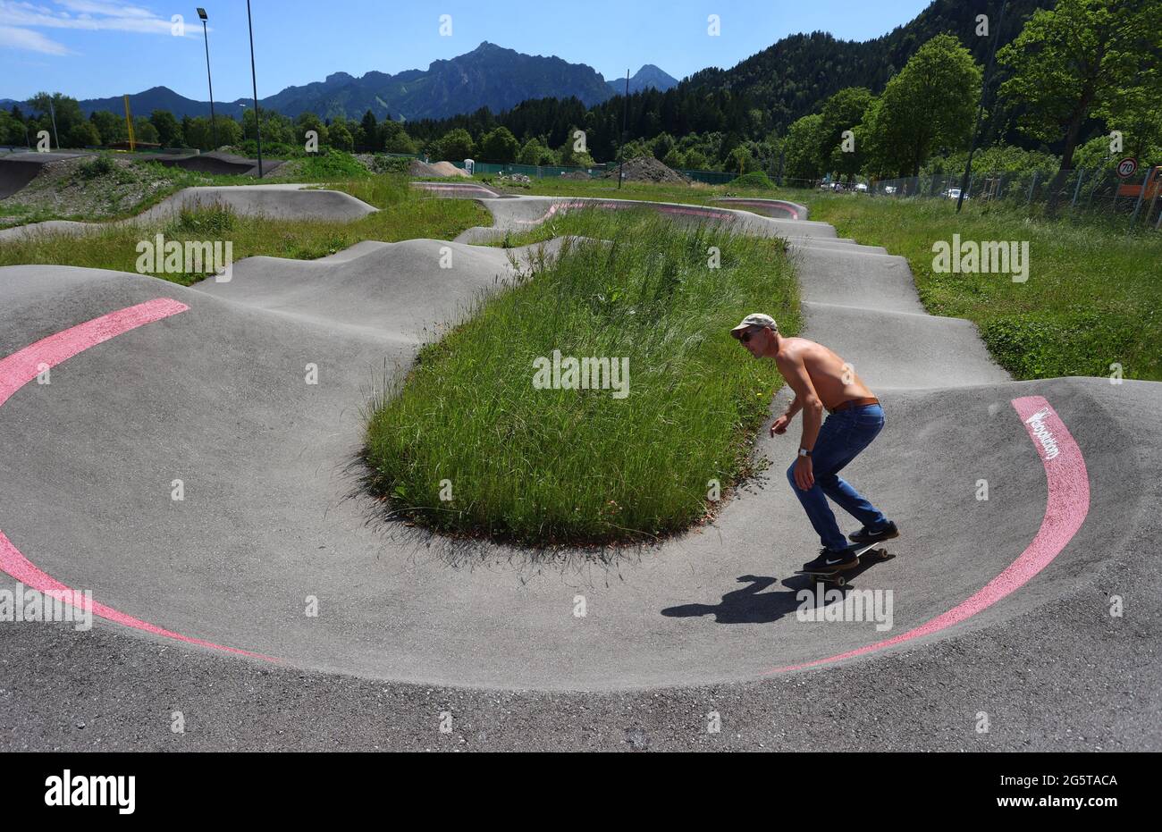 29. Juni 2021, Bayern, Füssen: Max fährt auf dem Erweiterungsbau der  Pumptrack-Anlage am Rande der Altstadt mit seinem Skateboard. Pumptracks  entstehen in immer mehr deutschen Städten, und nicht nur Radfahrer haben  Spaß