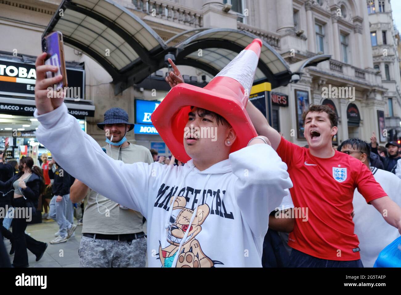 Ein Mann posiert für ein Selfie mit einem Verkehrskegel auf dem Kopf, nachdem England Deutschland mit 2:0 besiegt und ins Halbfinale des Euro-2020-Turniers vorrückte. Stockfoto