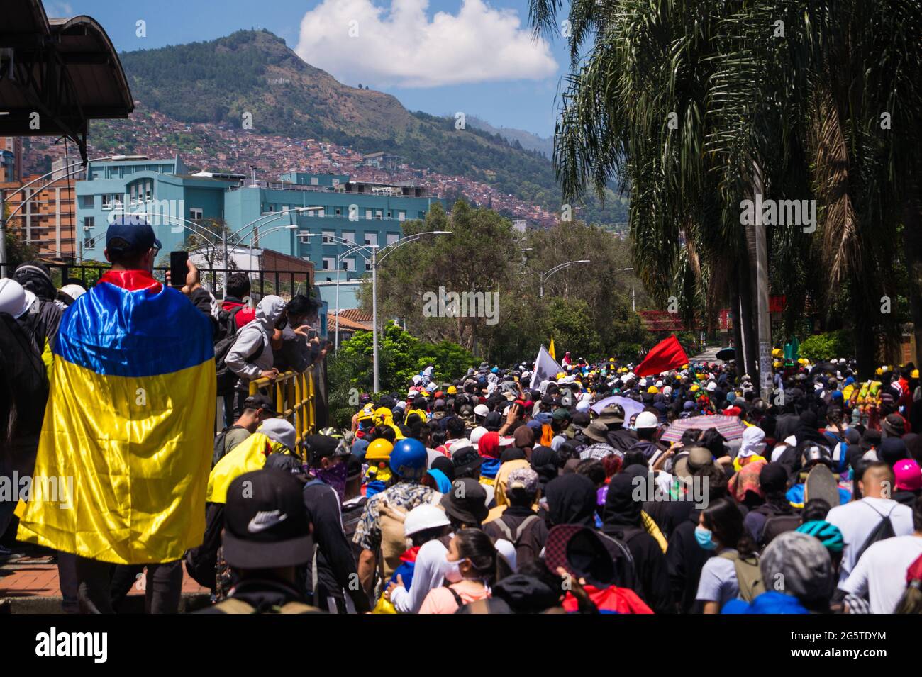 Medellin, Antioquia - Kolumbien am 28. Juni 2021. Eine Menschenflut wird als ein Demonstranten gesehen, der eine kolumbianische Nationalflagge trägt, während regierungsfeindliche Proteste inmitten politischer Spannungen gegen die Regierung von Präsident Ivan Duque zu Zusammenstößen zwischen Demonstranten und der kolumbianischen Bereitschaftspolizei (ESMAD) führen. Fälle von Polizeibrutalität und Ungleichheiten, da Kolumbien am 28. Juni 2021 in Medellin, Antioquia - Kolumbien einen zweiten Monat lang Proteste gegen die Regierung feiert. Stockfoto