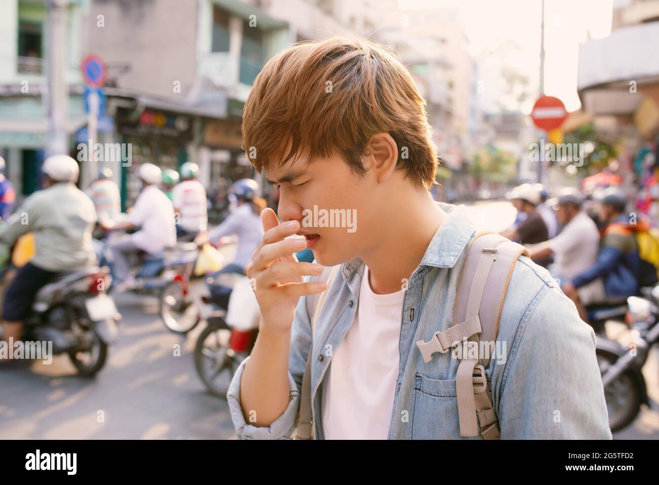 Mann niest auf der Straße, weil die Luft schlecht verschmutzt ist, Mann bekam eine Nasenallergie im Freien Stockfoto