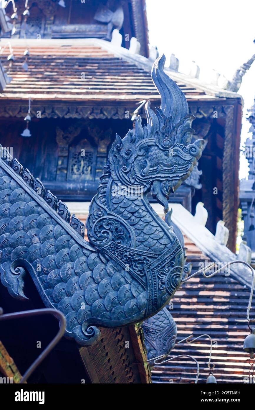 Der Kopf einer geschnitzten schwarzen Holzschlange wurde verwendet, um das Dach eines Tempels im Norden Thailands zu schmücken. Stockfoto