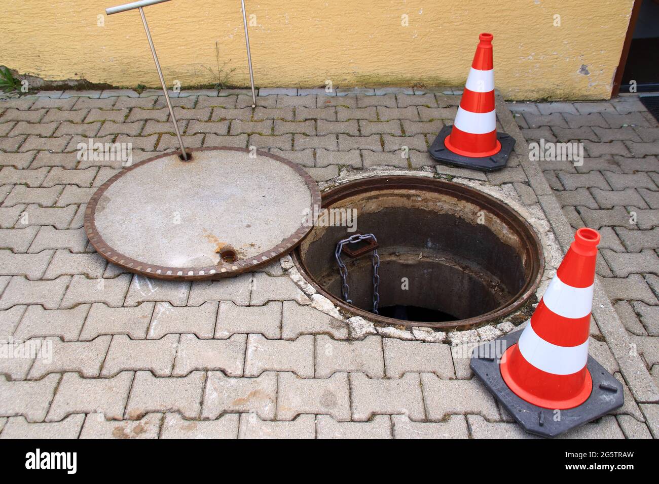 Das offene Mannloch ist mit Verkehrskegeln gesichert Stockfoto