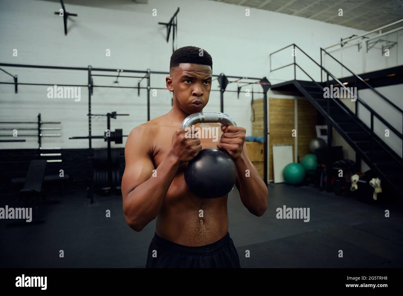 Afroamerikanischer Mann macht Cross-Training im Fitnessstudio. Mischrasse männlich mit einer Kettlebell während des Trainings. Hochwertige Fotos Stockfoto