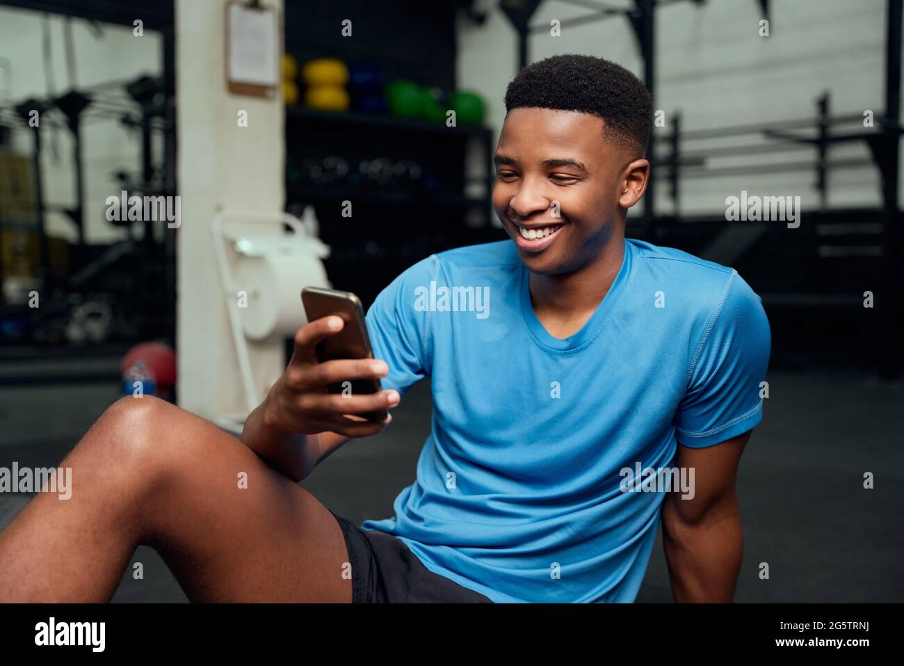 Afroamerikanischer Mann, der auf sein Telefon schaut. Nahaufnahme von männlichen Scrolling-Apps auf seinem Handy, während er sich im Fitnessstudio ausruhte. Hochwertige Fotos Stockfoto