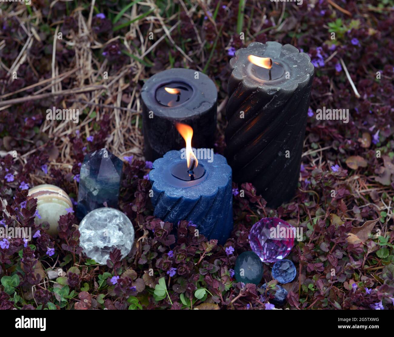 Beltane Zauberritual mit brennenden Kerzen, Kristallen und magischen Objekten draußen. Esoterischer, gotischer und okkulter Hintergrund, Halloween Mystic und Wicca Konz Stockfoto