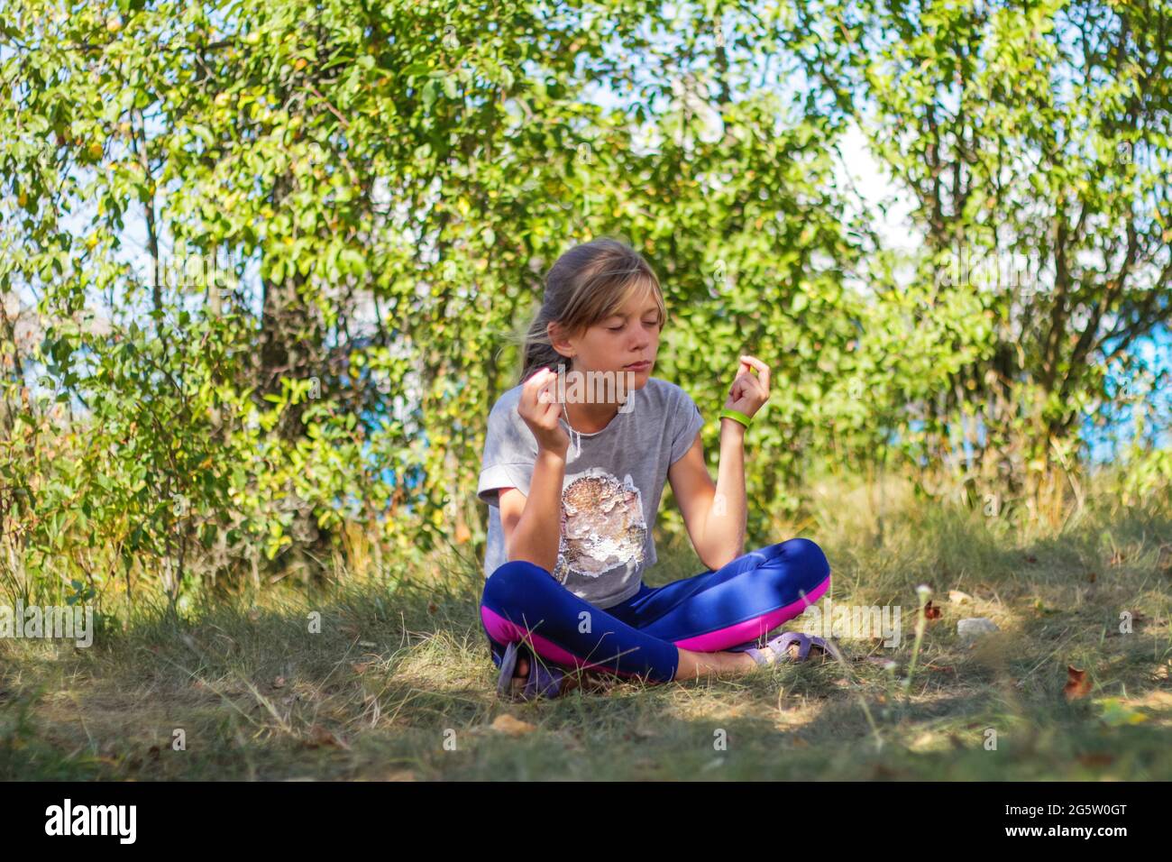 Defocus caucasian preteen Mädchen praktiziert Yoga im Park, Wald, im Freien, draußen. Meditation und Konzentration. Wellness gesunder Lebensstil. Yoga-Mädchen Stockfoto