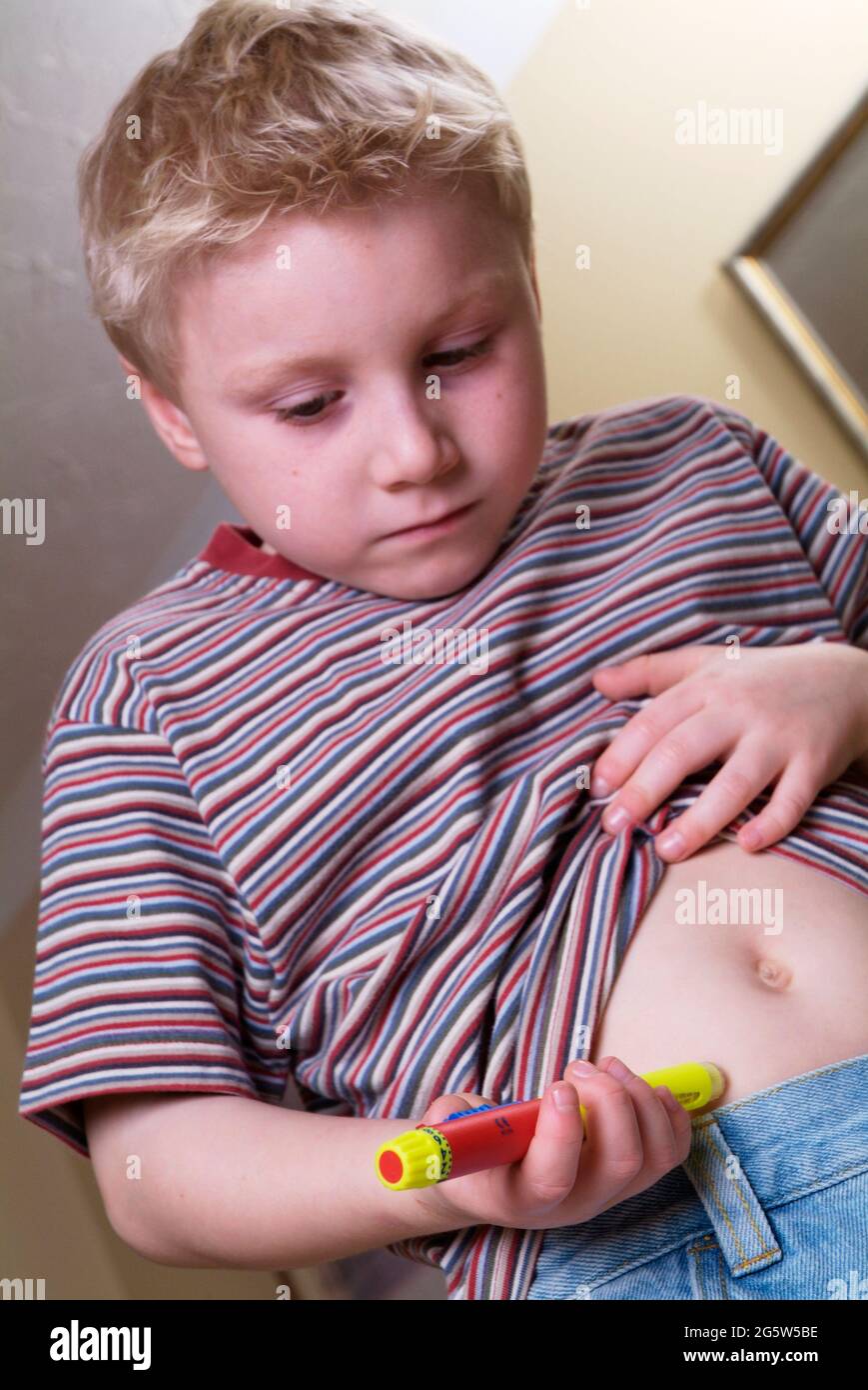 Der Junge injiziert selbst Insulin mit einem Insulinstift in seinen Bauch Stockfoto