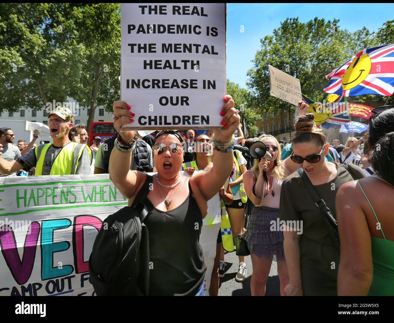 London, Großbritannien. Juni 2021. Ein Protestler hält ein Plakat hoch, auf dem die anhaltende Gefahr der Sperrung von Kindern hervorgehoben wird, während andere im Hintergrund Parolen singen.Demonstranten versammeln sich vor der Downing Street, um gegen Boris Johnsons Ankündigung einer Verlängerung der Sperrbestimmungen im Vereinigten Königreich zu protestieren, die ihrer Meinung nach auch ihre Menschenrechte verletzen Protest gegen das fortgesetzte Tragen von Masken und das Unterwerfen des Impfprogramms. Quelle: Martin Pope/SOPA Images/ZUMA Wire/Alamy Live News Stockfoto