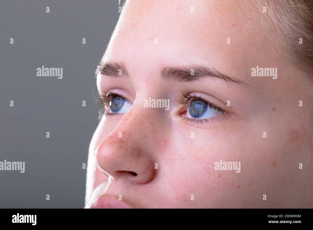 Nahaufnahme der blauen Augen einer kaukasischen Geschäftsfrau, isoliert auf grauem Hintergrund Stockfoto
