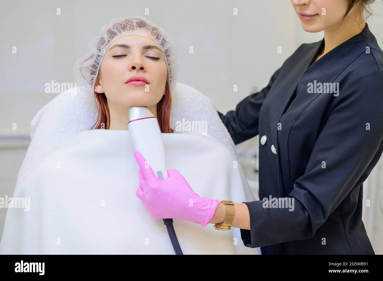 Der Griff des Hochfrequenzgerätes am Kinn eines weiblichen Gesichts während eines Schönheitsverfahrens zur Hautverjüngung. Kosmetikerin macht eine Hardware Stockfoto