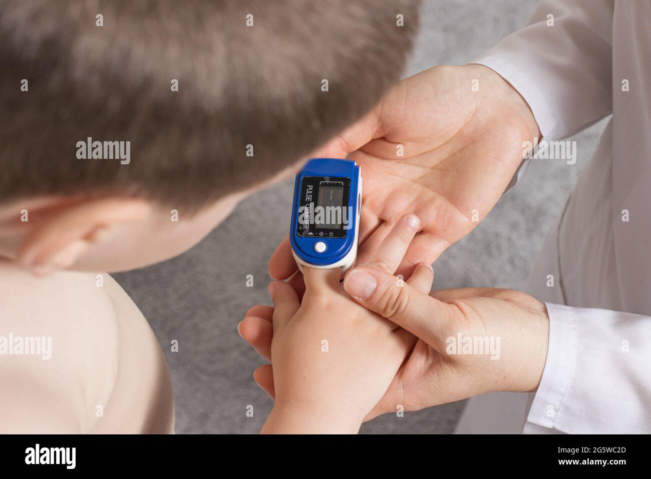 Der Kinderarzt misst den Sauerstoffgehalt im Blut des Kindes mit einem Pulsoximeter. Lungenentzündung und Coronavirus bei Kindern Stockfoto