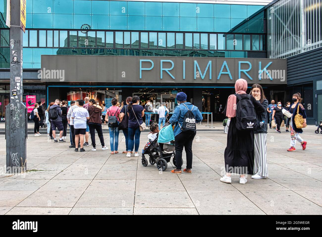 Menschen mit Gesichtsmasken stehen während der Corona Pandemic, Alexanderplatz, Mitte, Berlin vor dem Primark Clothing Store an Stockfoto