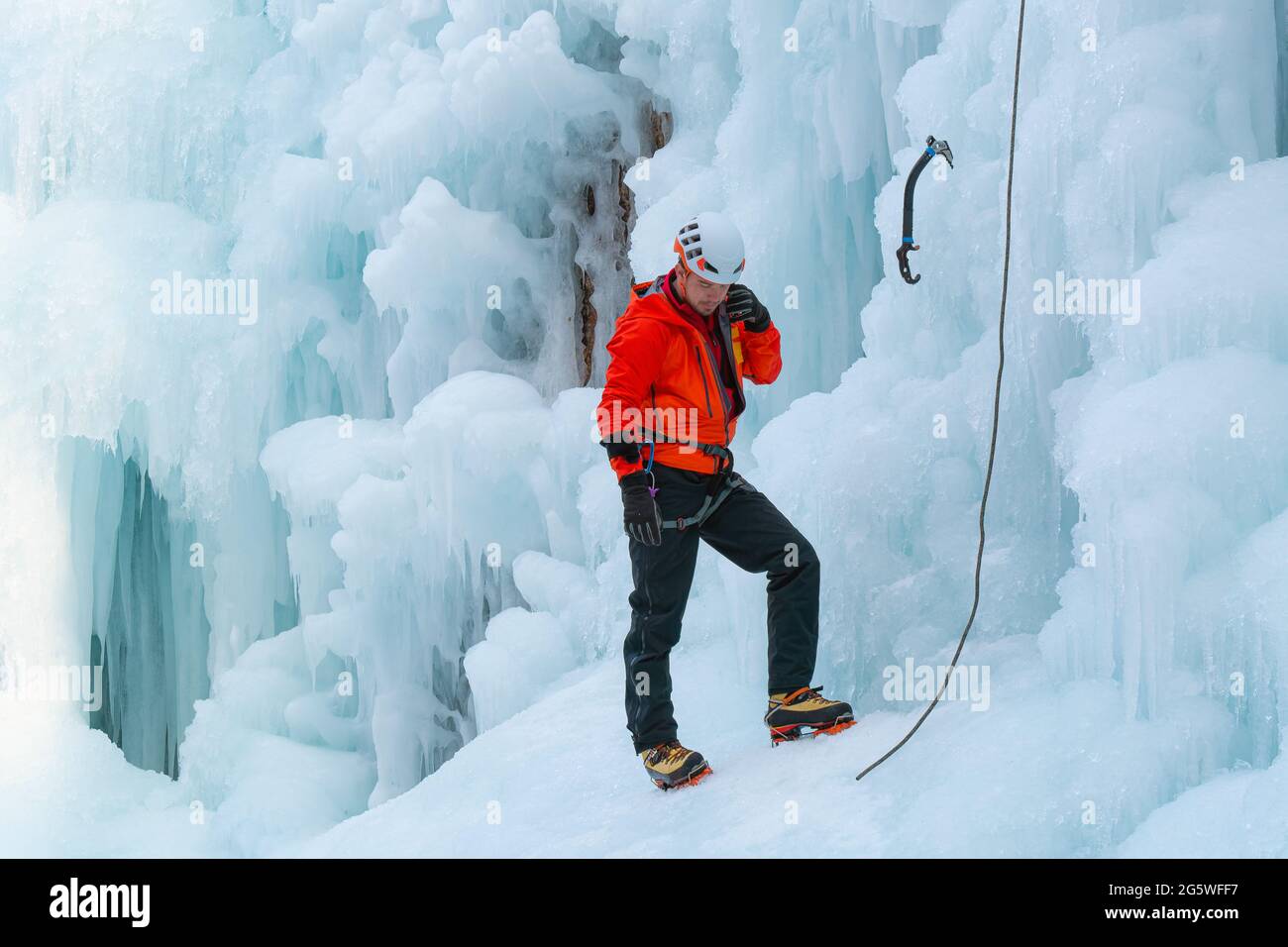 Männlicher Eiskletterer, der sich auf einen Aufstieg vorbereitet Stockfoto