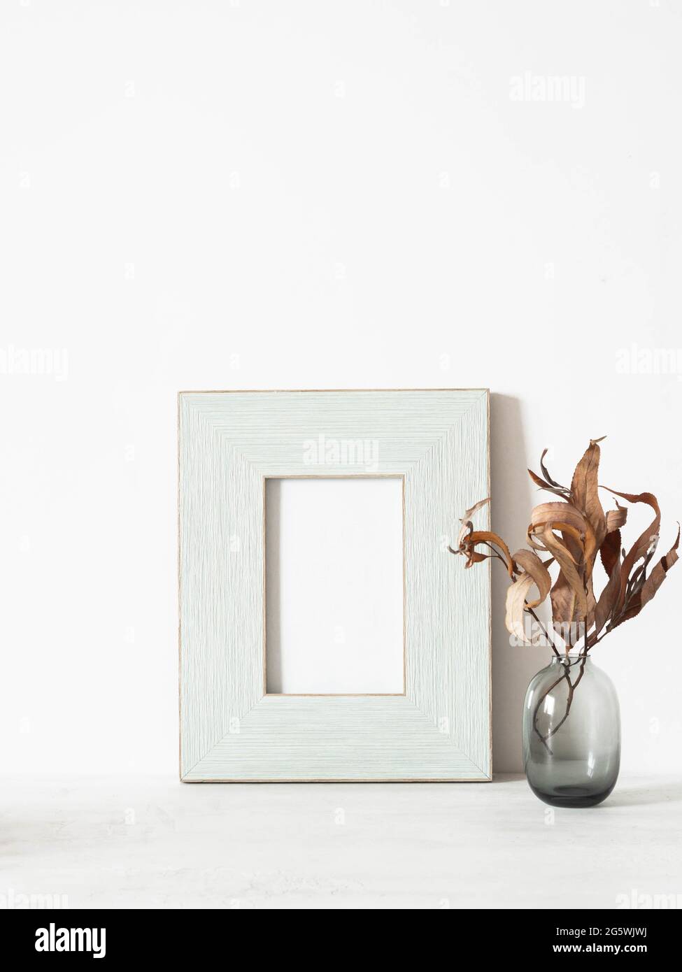 Home Stillleben von trockenen Herbstzweigen in Vase und Holz blauen Pastellrahmen auf weißem Tisch. Speicherplatz kopieren. Vorderansicht Stockfoto