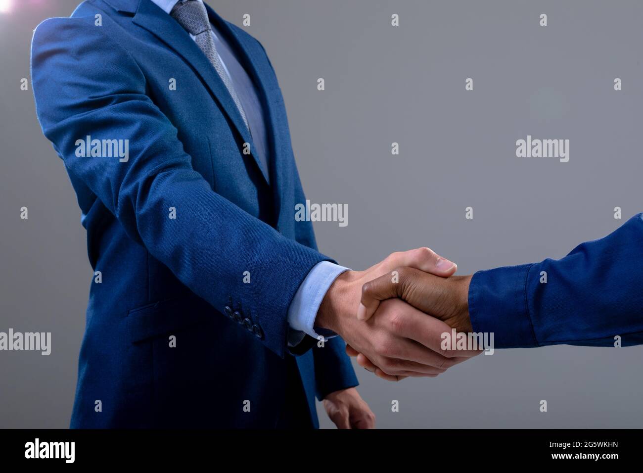 Kaukasische und afroamerikanische Geschäftsleute schütteln sich die Hände, isoliert auf grauem Hintergrund Stockfoto