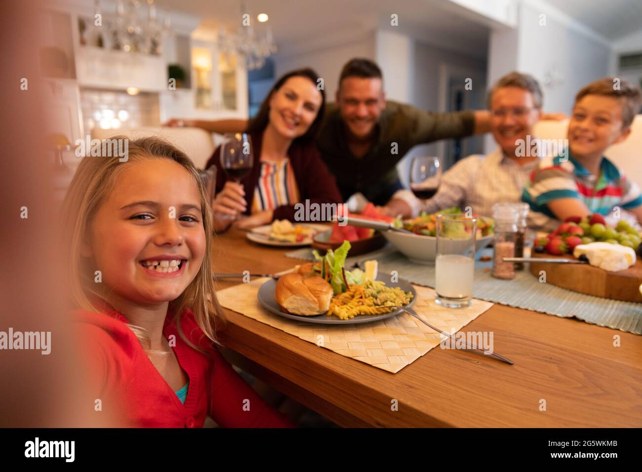 Kaukasisches Paar mit Sohn, Tochter und Großvater, die zu Hause am Tisch sitzen und zusammen essen Stockfoto