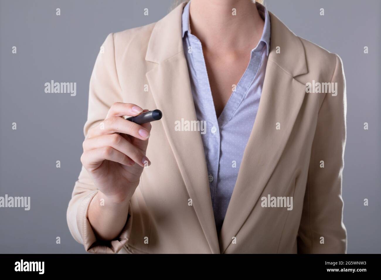 Mittelteil der kaukasischen Geschäftsfrau mit Stift, isoliert auf grauem Hintergrund Stockfoto