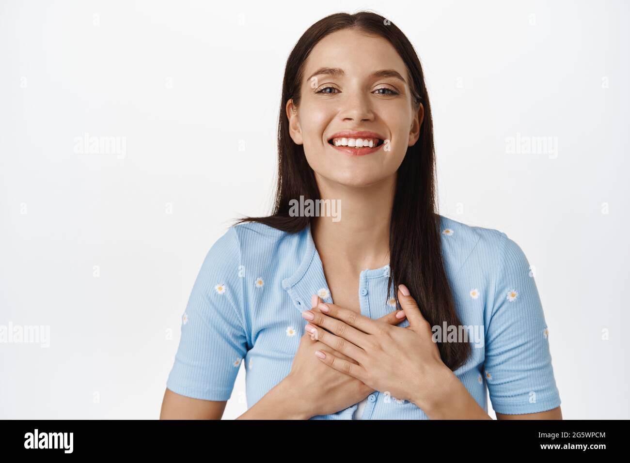 Danke. Dankbares Mädchen, das die Hände auf der Brust hält, glücklich lächelt und die Kamera anschaut, Dankbarkeit zum Ausdruck bringt, Freude, smeth zu empfangen, über Weiß stehend Stockfoto