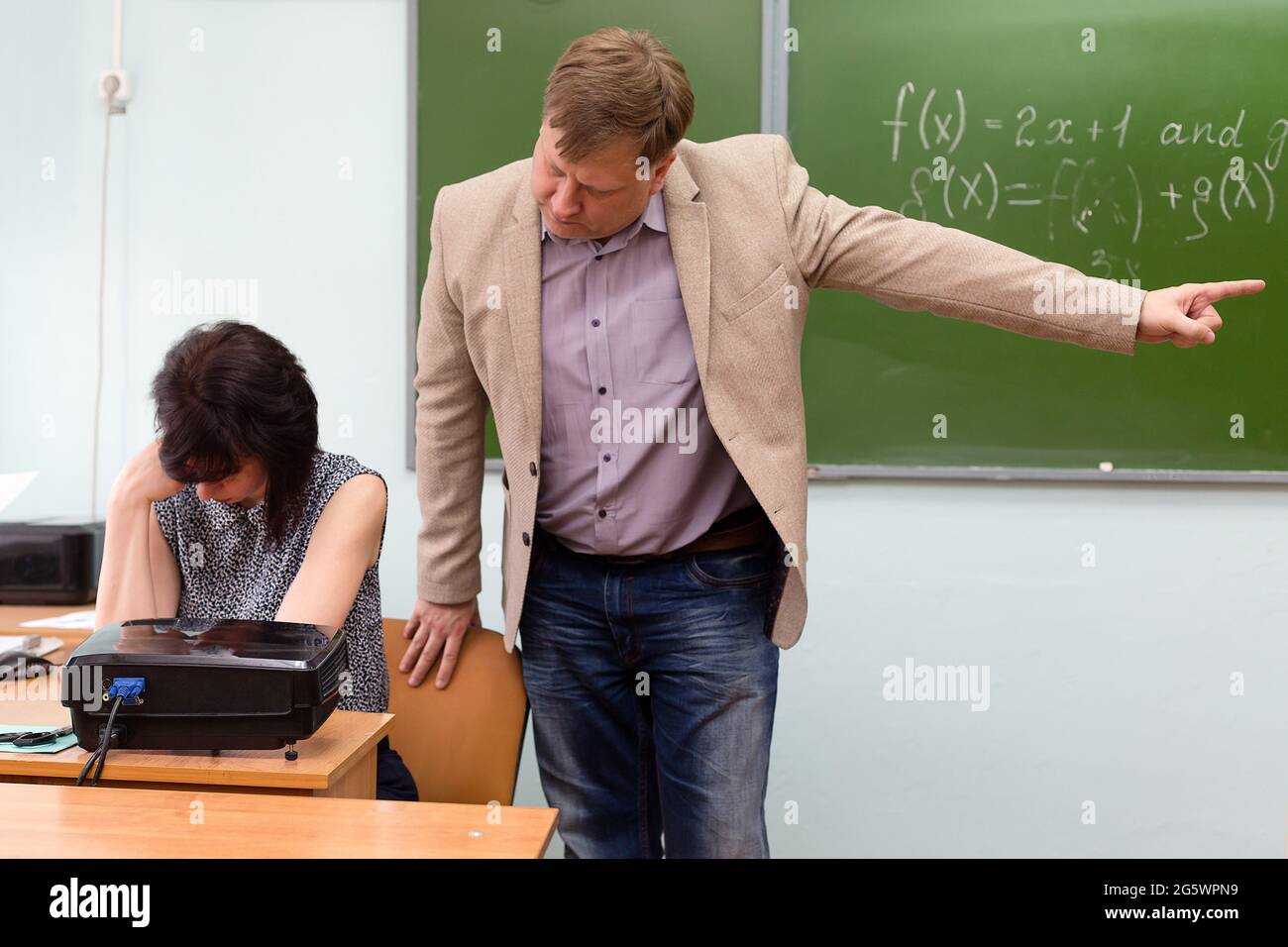 Der Regisseur schimpft den Lehrer für eine unerfüllte Aufgabe und wirft ihn mit einer Handbewegung aus dem Klassenzimmer. Stockfoto