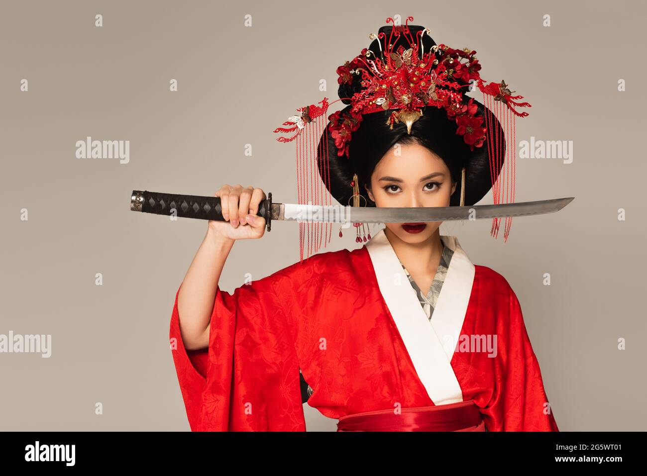 Japanische Frau hält Schwert in der Nähe Gesicht isoliert auf grau  Stockfotografie - Alamy