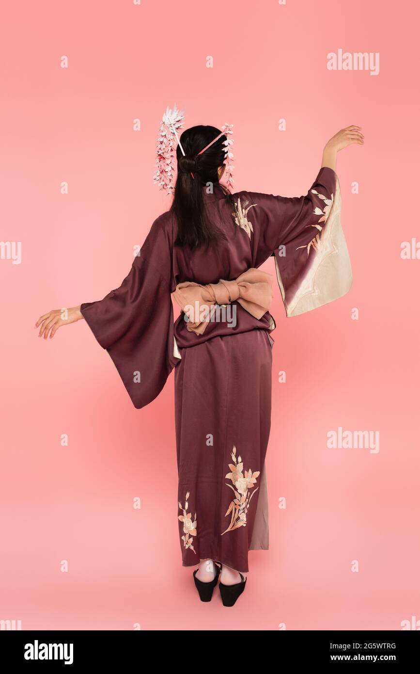 Rückansicht einer jungen Frau im Kimono und traditioneller Frisur auf rosa Hintergrund Stockfoto