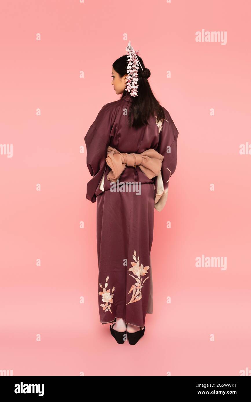 Seitenansicht einer asiatischen Frau in traditioneller Tracht auf rosa Hintergrund Stockfoto