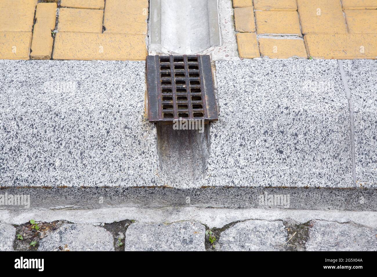 Drain Rost-System, Grill für die Entfernung von Regenwasser von Wanderwegen durch Graben und Loch in Granit-Randstein auf der Straße schließen, niemand. Stockfoto
