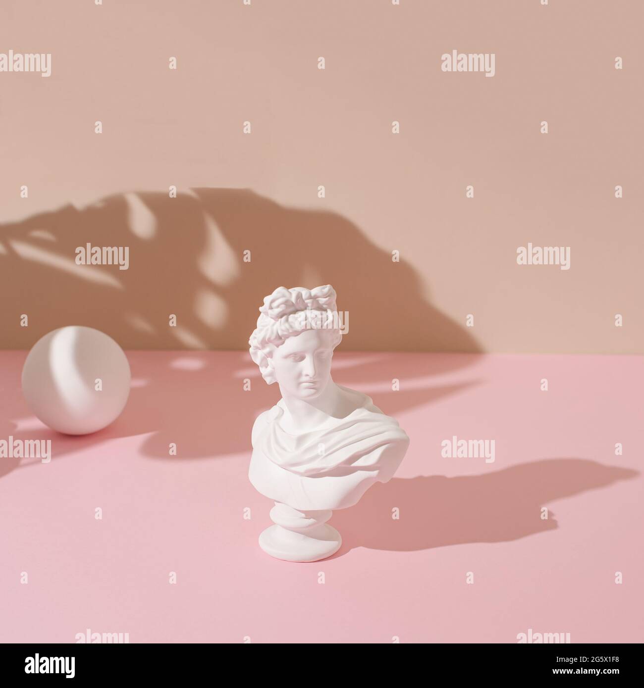 Kreatives Layout mit der Skulptur eines antiken Apollo und einer weißen Kugel auf pastellrosa und beigen Hintergrund. Konzeptkunst mit minimalistischer Ästhetik. Stockfoto