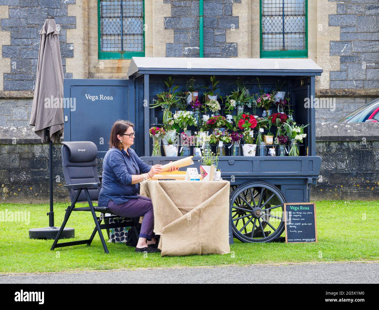 Floristin mit einem Anhänger im Vintage-Stil auf einem Markt, Bude, Cornwall, Großbritannien Stockfoto