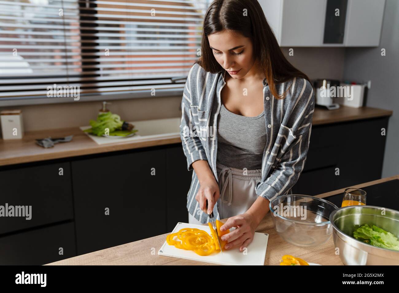 Charmante fokussierte Frau, die Salat in der gemütlichen Küche zu Hause zubereitet Stockfoto