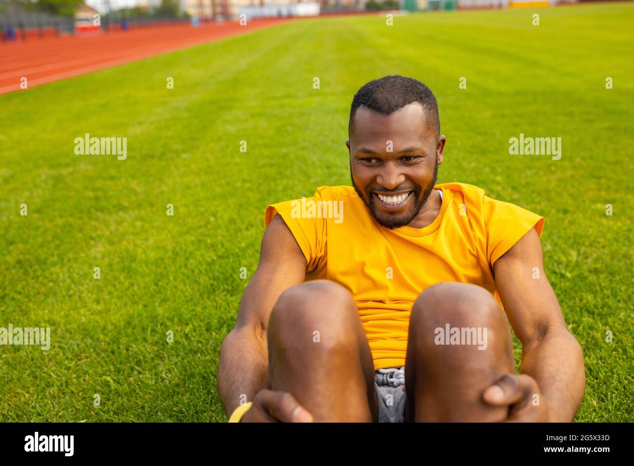Nahaufnahme Porträt eines gesunden jungen Afro-amerikanischen schwarzen Mannes, der im Stadion knirscht, seinen Körper fit hält und Aufwärmübungen macht Stockfoto