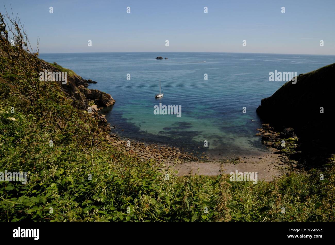 Eine Yacht, die im klaren Wasser Pudcombe Cove in der Nähe von Colton Fishacre, South Hams, Devon, Großbritannien, festgemacht ist Stockfoto