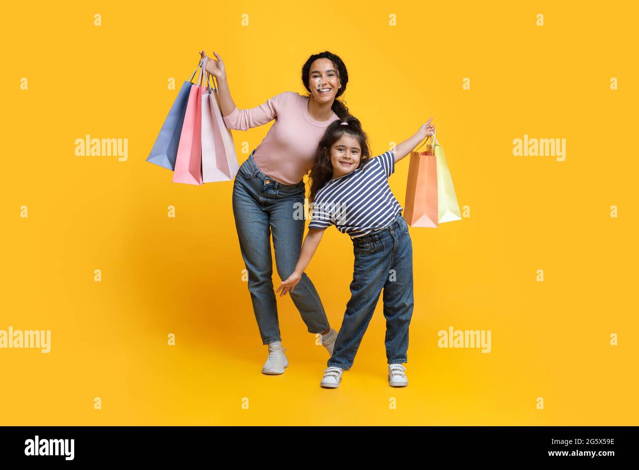 Familienshoppen. Fröhliche Arabische Mutter Und Kleine Tochter Posieren Mit Eingekauften Taschen Stockfoto